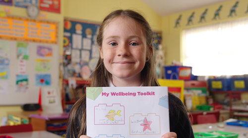 Young Girl Holding up wellbeing toolkit